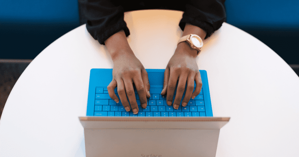 Aperson typing on a laptop with a blue keyboard